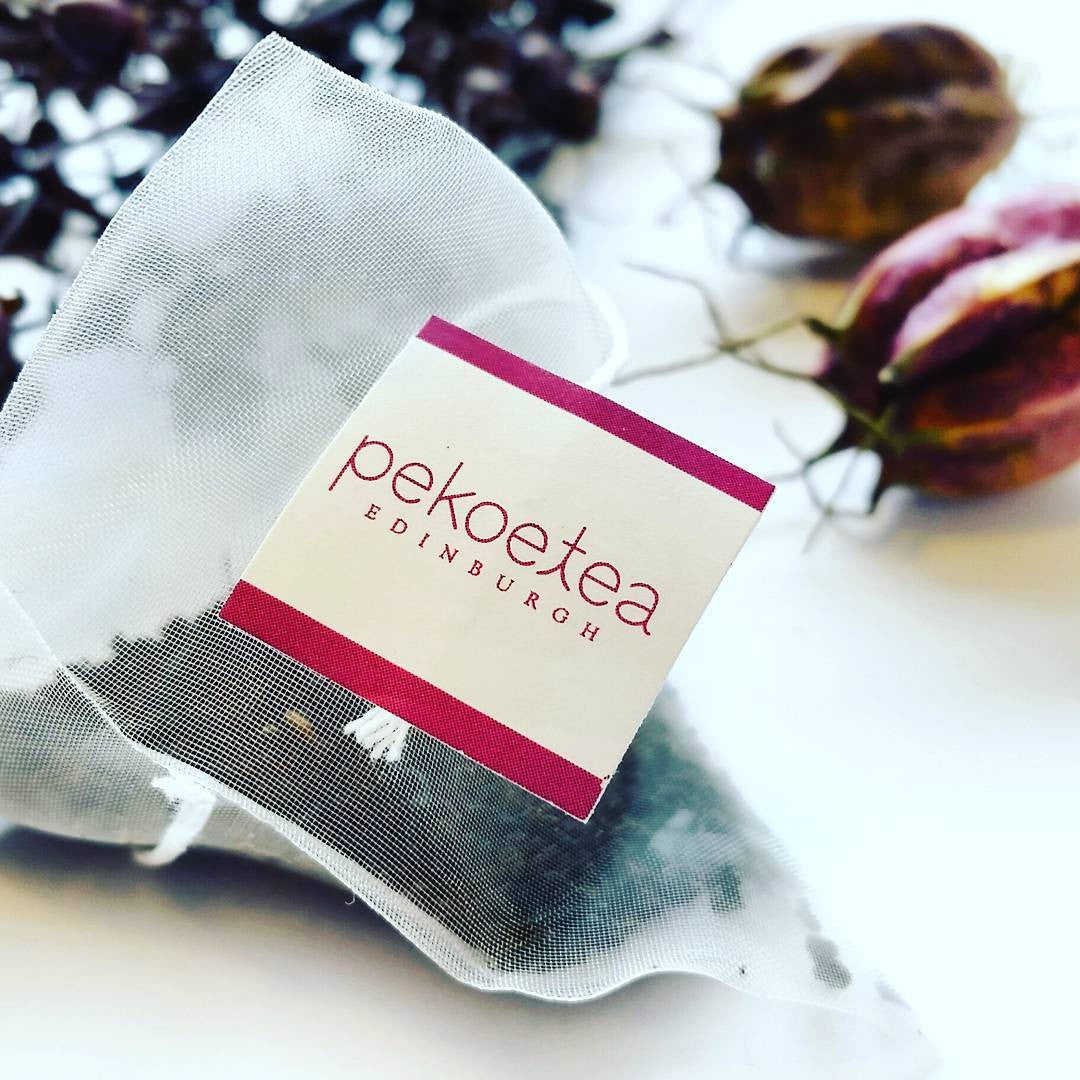 A white sheer mesh breakfast blend tea bag with a rectangular label featuring the pekoetea edinburgh logo in red script