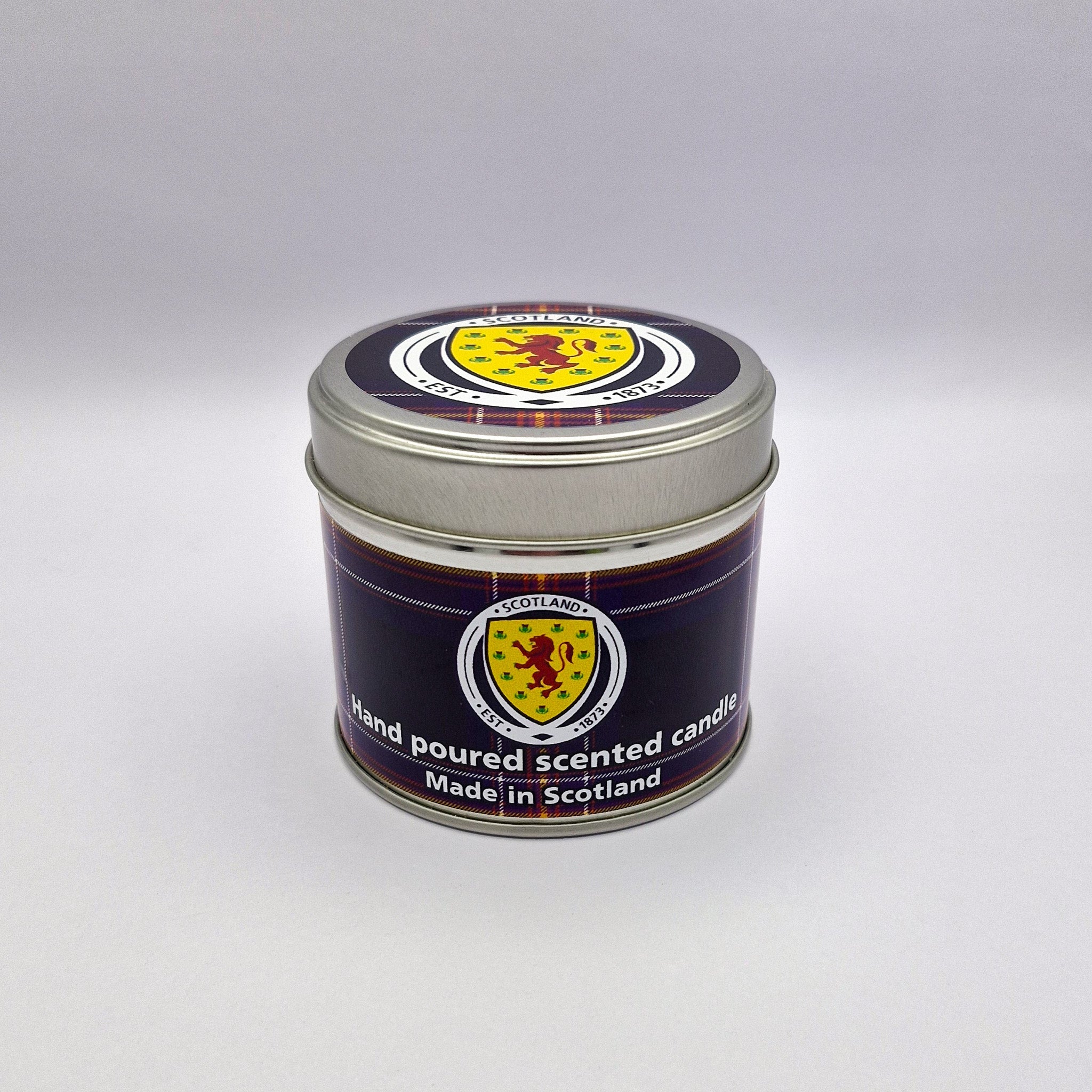 A hand-poured scented candle in a metal tin with the scottish emblem on a dark blue and red tartan label