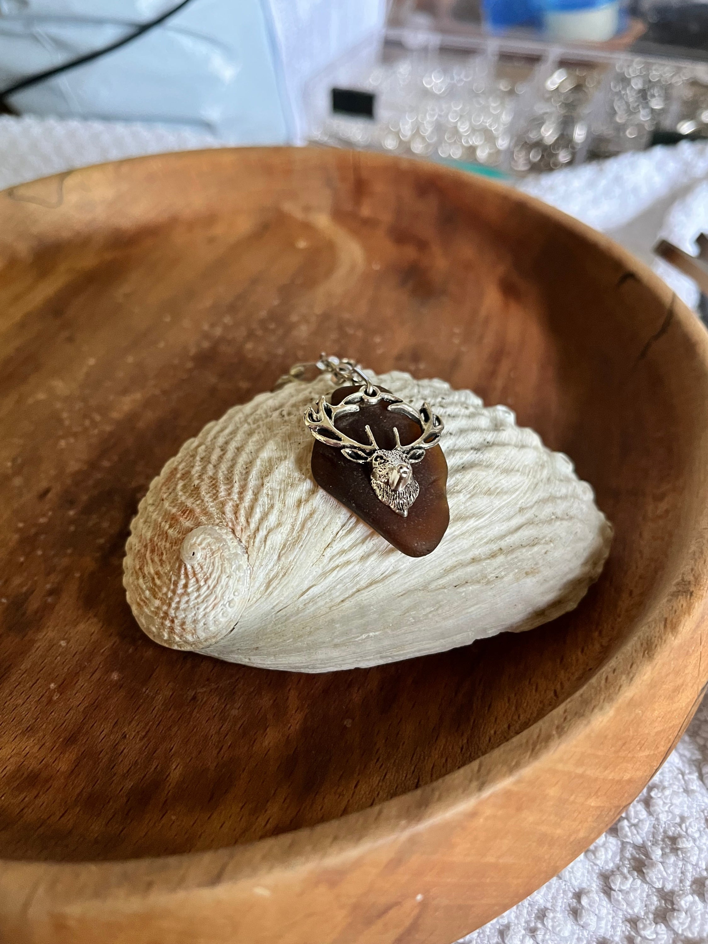 Dark brown sea glass stag head keyring on white seashell