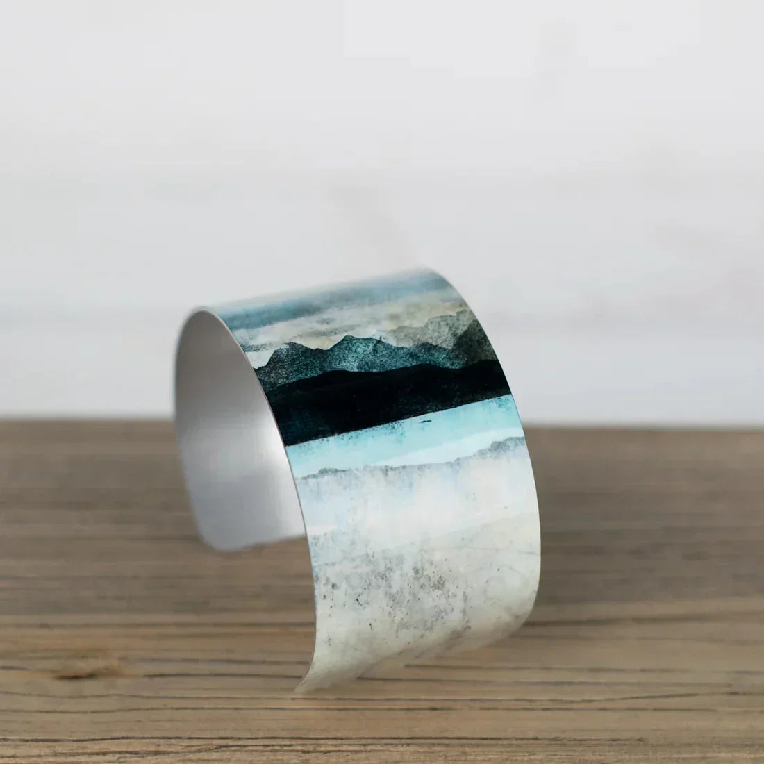 Sleek silver Skye cuff bracelet from Bealach Bangle with teal landscape design
