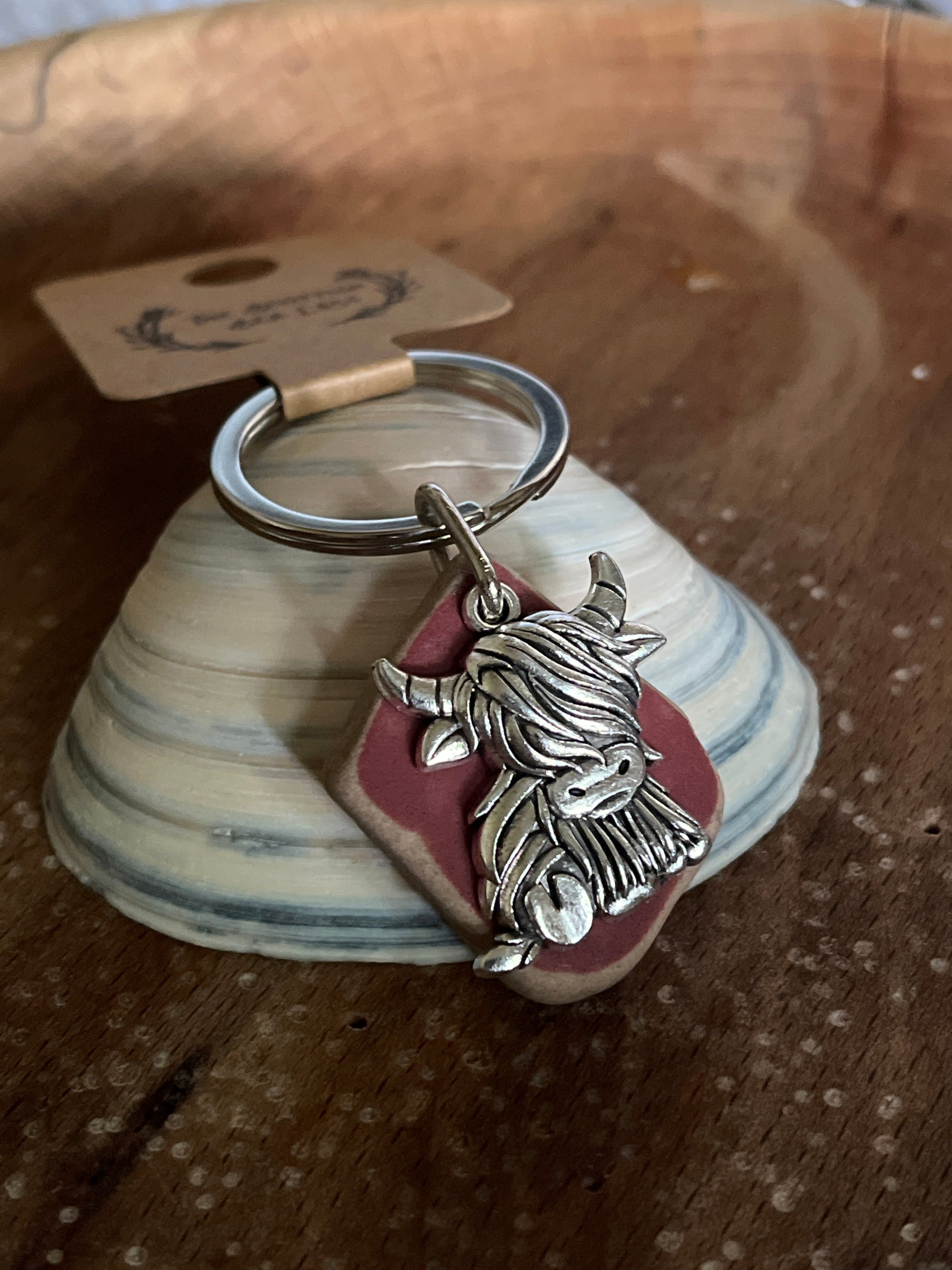 Silver highland cow seaglass keyring with metallic charm on red ceramic base