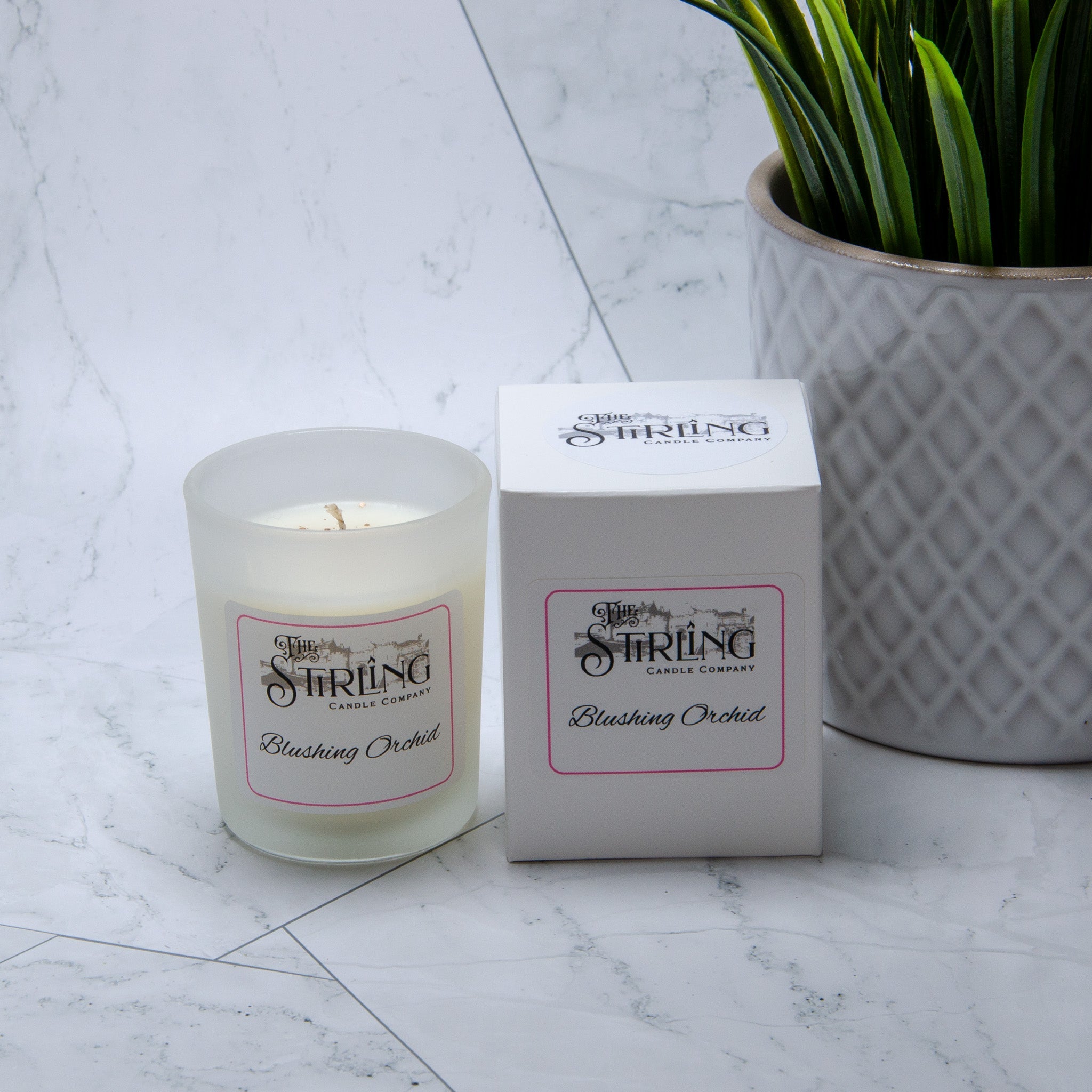 A frosted glass small candle with white wax and a blushing orchid label from the string candle company