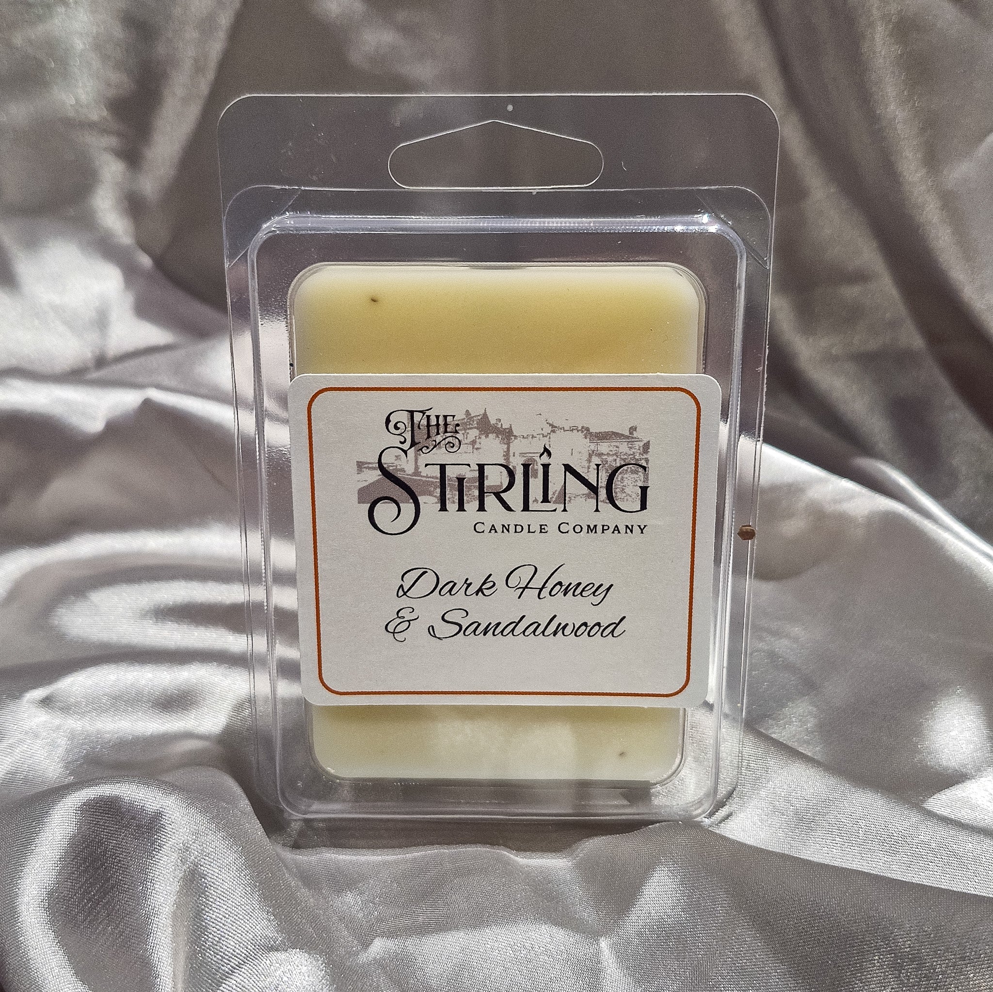 A pale yellow dark honey and sandalwood wax melt in a clear plastic clamshell from the Stirling Candle Company
