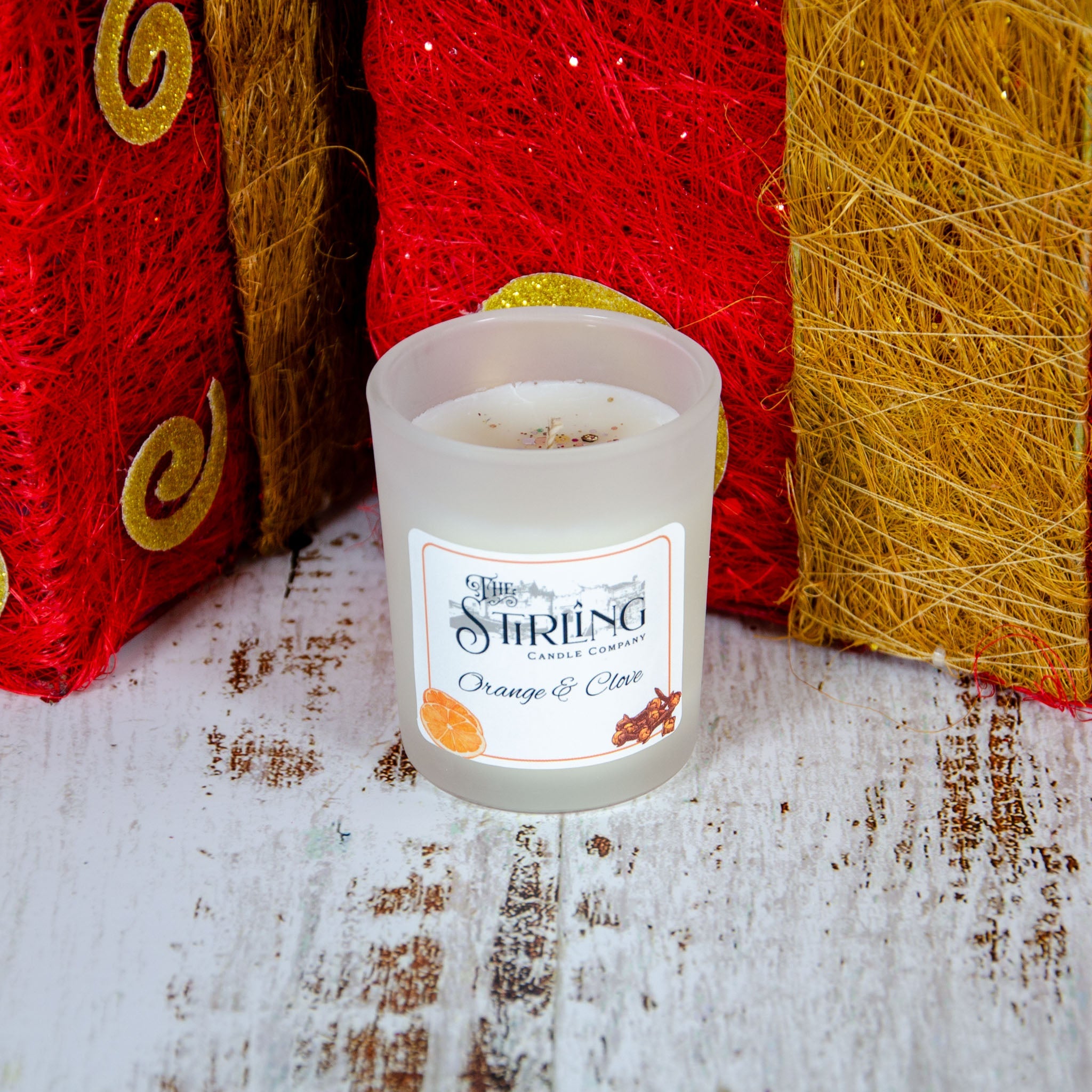 A frosted glass small candle in a cylindrical container scented with orange and clove from the stirring candle company