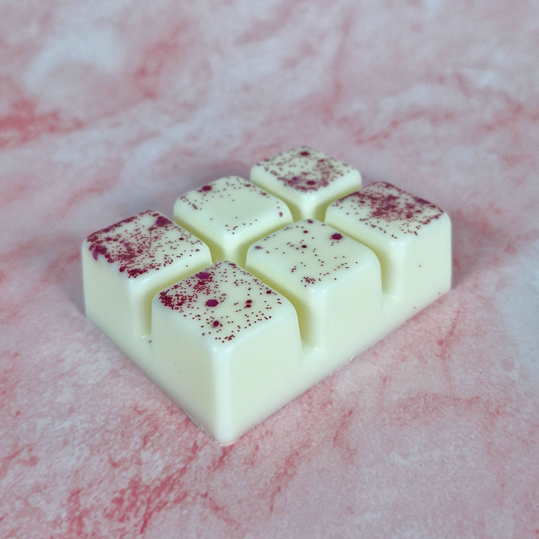 Cream-colored rose petals wax melt clamshell bar with six square sections lightly dusted with red speckles
