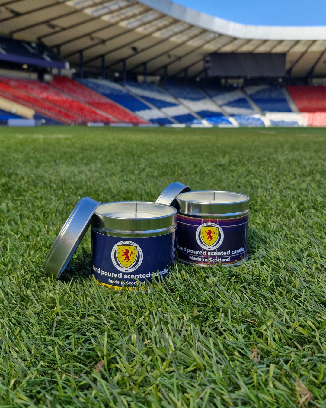 Two navy blue cylindrical metal travel tin candles with silver lids featuring scottish thistle hand-poured in scotland