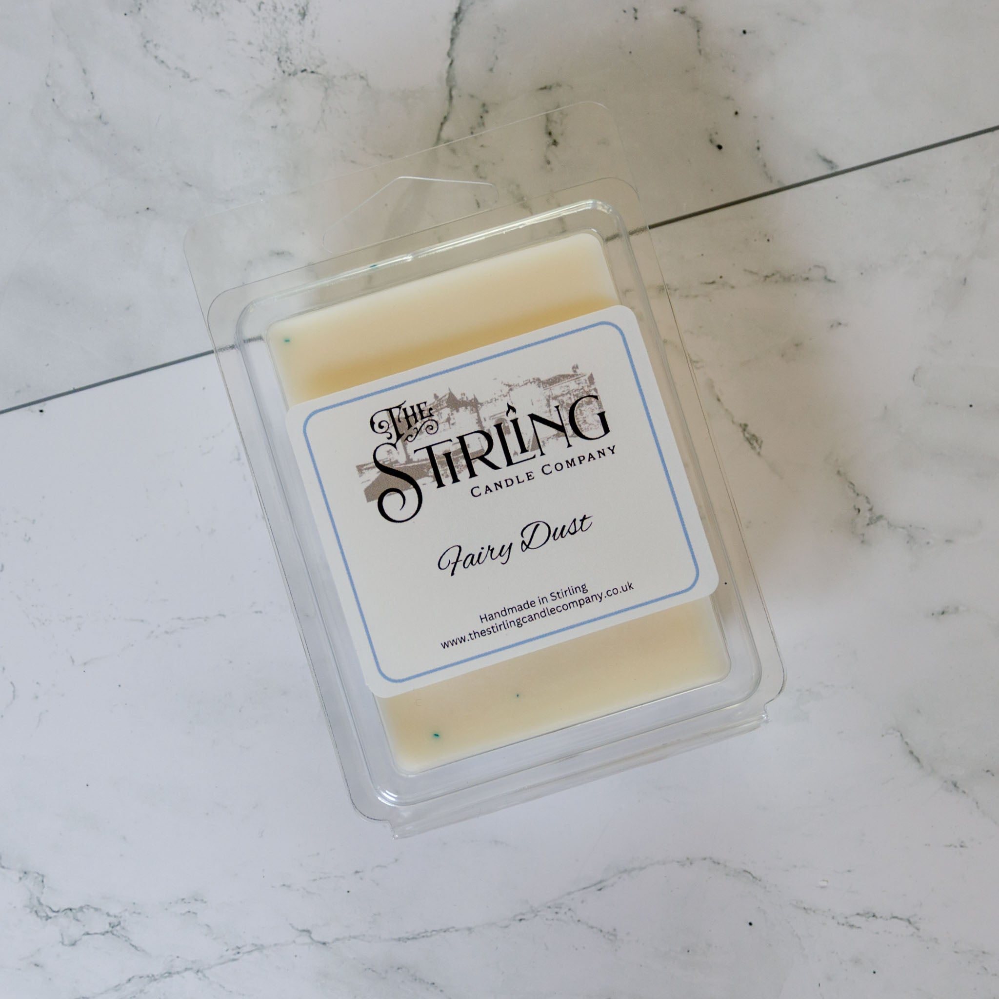 A creamy white fairy dust wax melt in a clear plastic clamshell package from the Stirling Candle Company