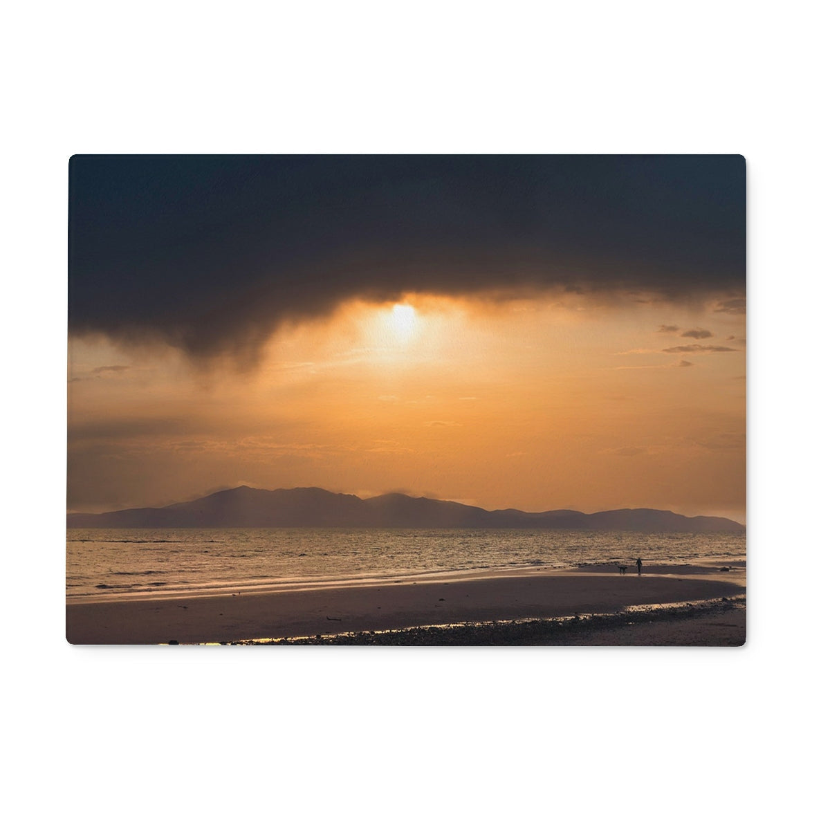 Arran Stormy Sunset Glass Chopping Board featuring a beach sunset with dramatic clouds and distant mountains