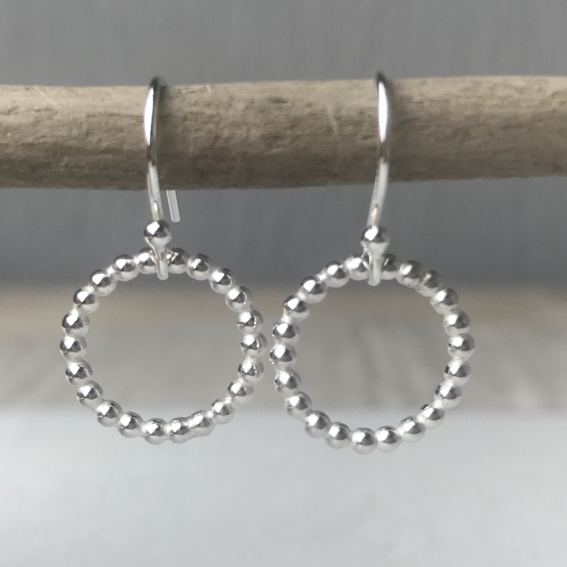 Silver beaded hoop earrings with a delicate textured design featuring a beaded halo style