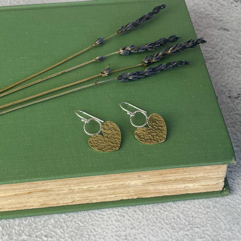 Beaten brass heart earrings with hammered gold tone on green book