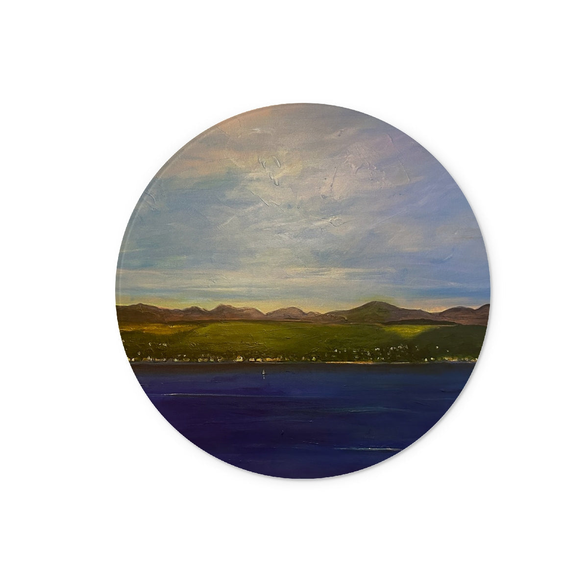Circular landscape painting of mountains, town, and water on The Biggie Glass Chopping Board