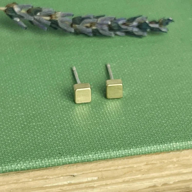 A pair of minimalist gold-toned brass cube stud earrings with a sleek polished finish