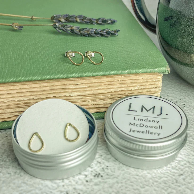 Brass teardrop stud earrings in gold displayed in a silver tin from lindsay mcdowall jewellery