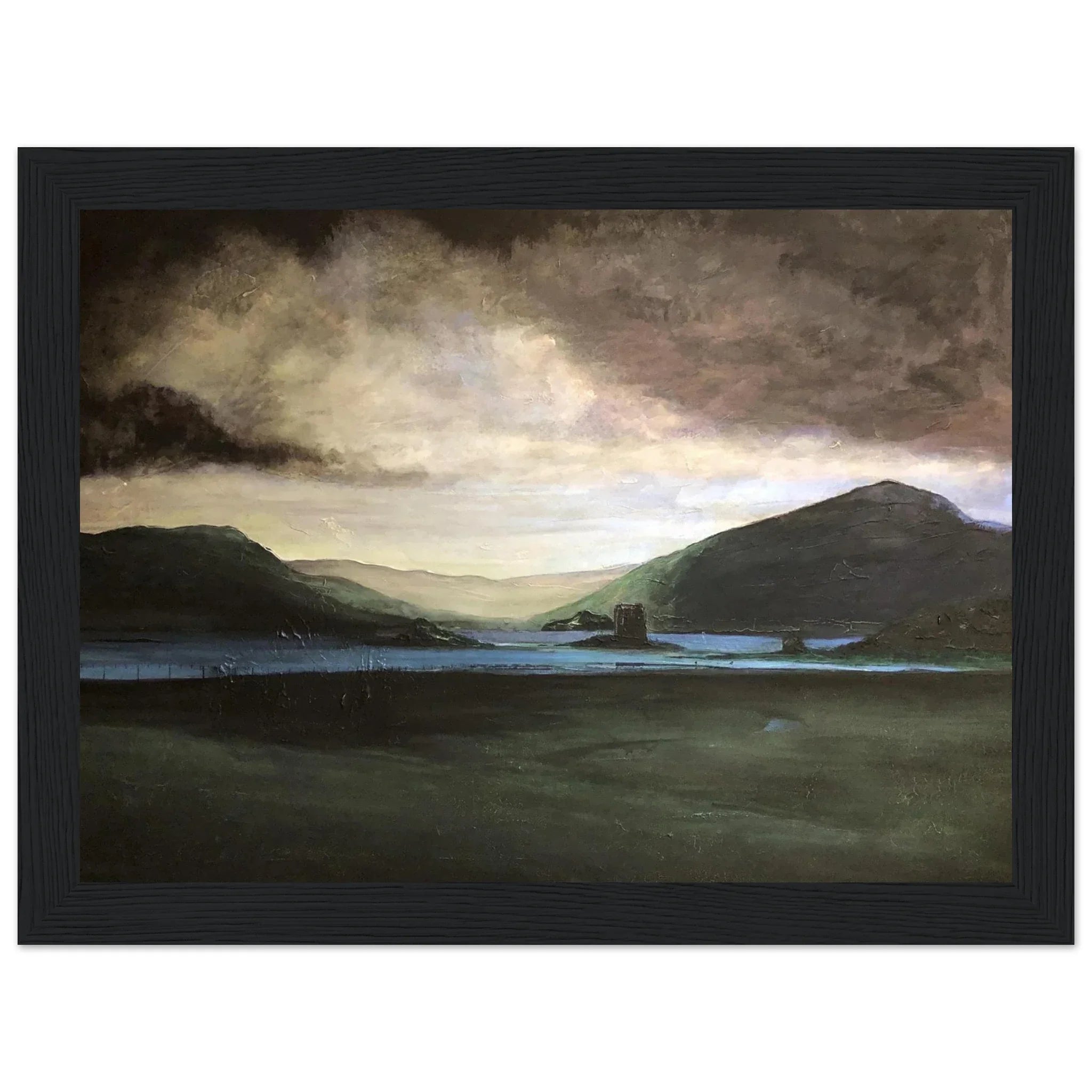 Brooding castle in moody Scottish landscape with dark mountains, water, stormy skies