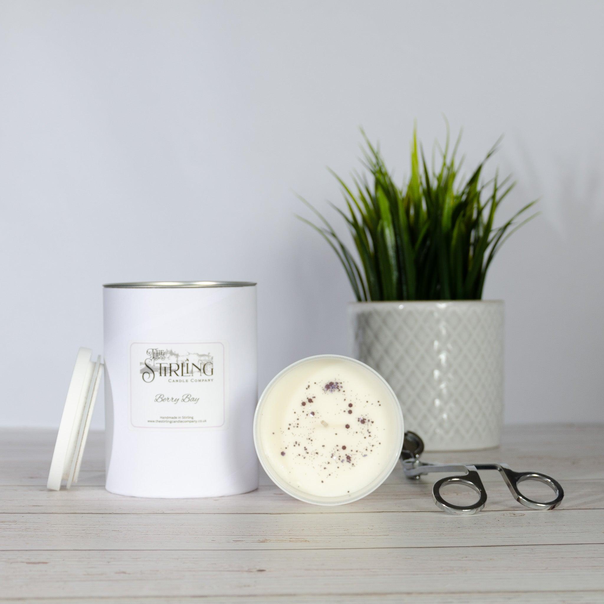 White cylindrical berry bay large candle with silver lid and creamy wax featuring dark speckles on surface