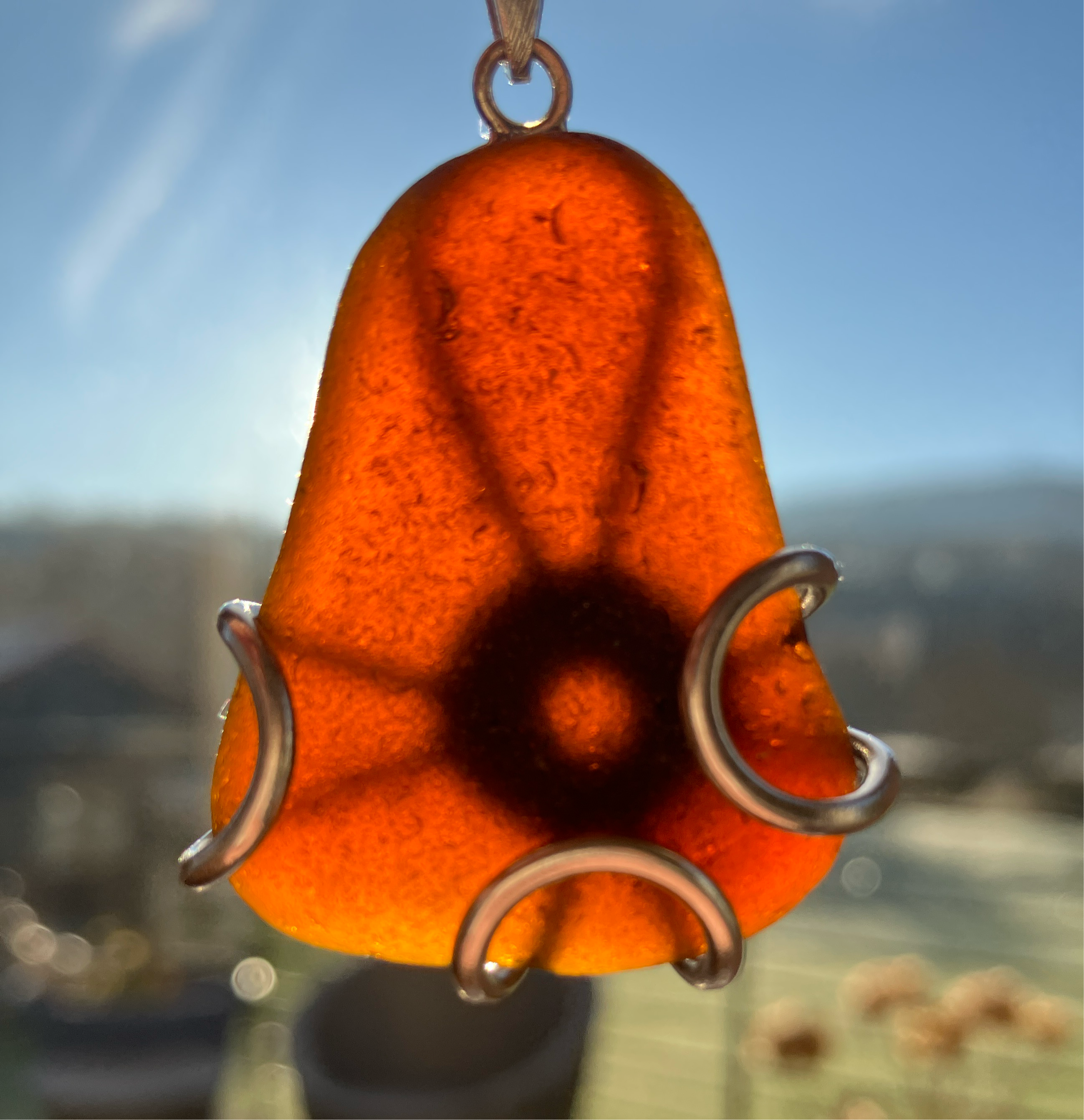 Orange Scottish Seaglass Pendant with dark circular design and silver wire wrapping