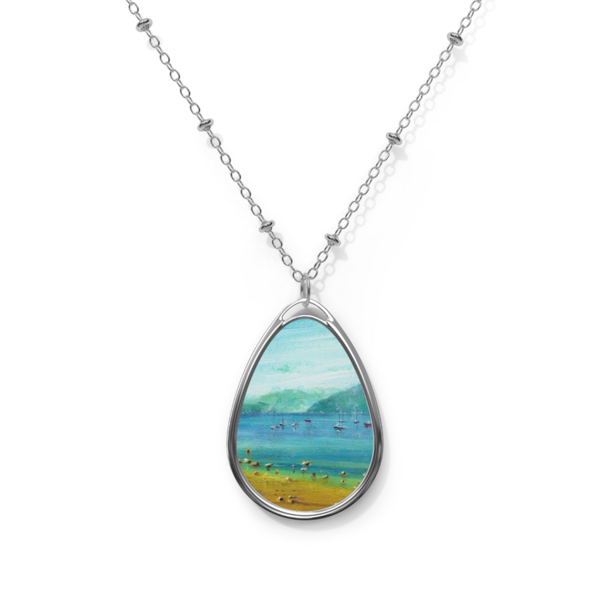 Silver-toned necklace with oval pendant showcasing a painted Scottish coastal landscape