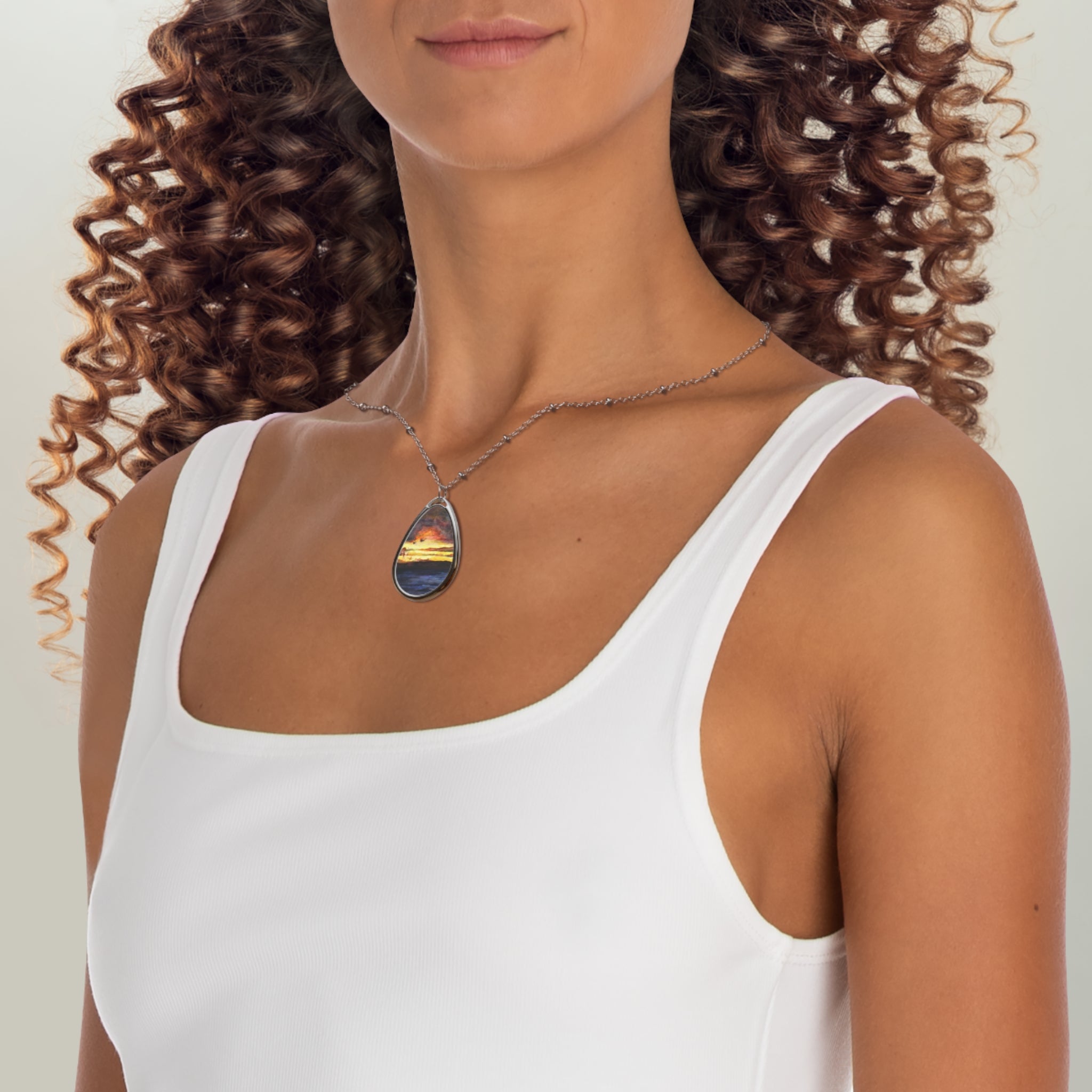 Woman with curly brown hair wearing a white tank top and oval pendant necklace showcasing Clyde Sunset Scottish Jewellery