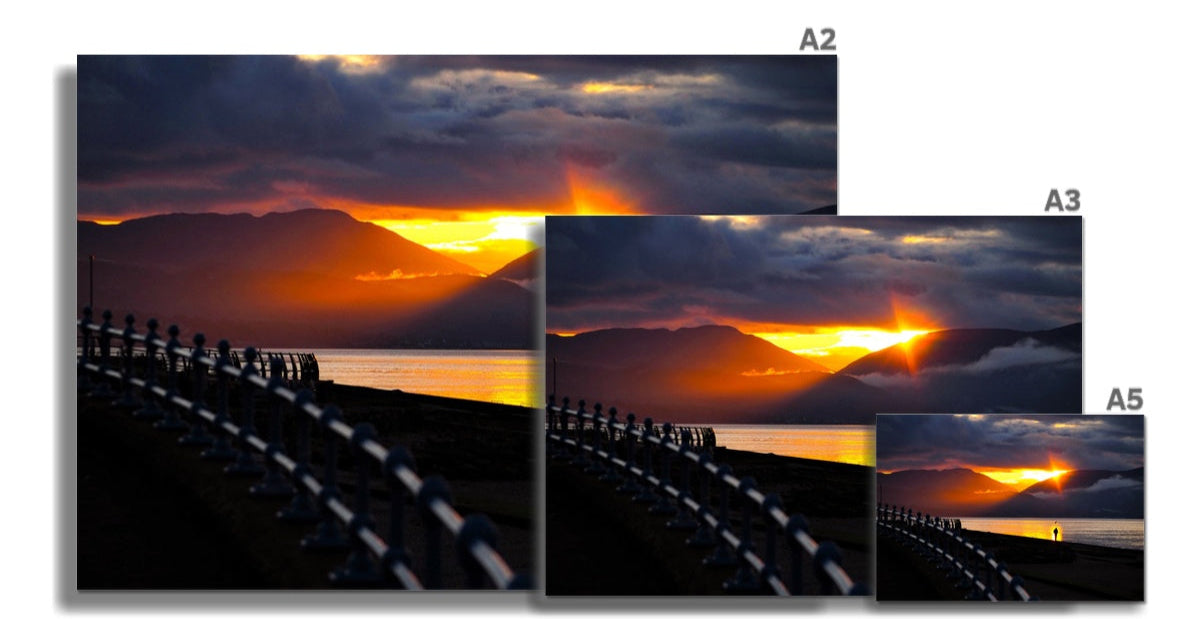 Sunset reflection fine art print of a radiant orange sun breaking through clouds over mountains with silhouetted figures