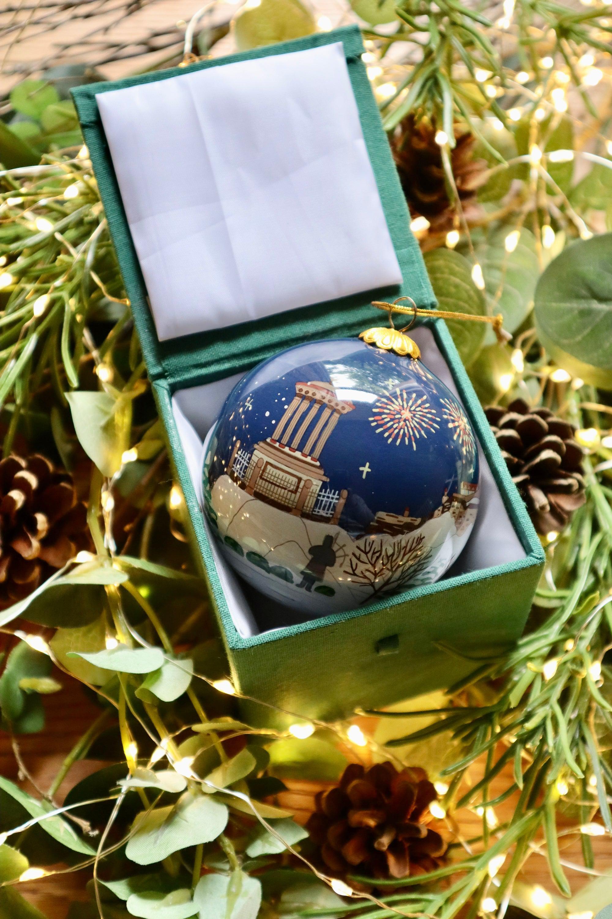 A glossy navy blue scottish christmas decoration bauble featuring a classical building with fireworks in a velvet box