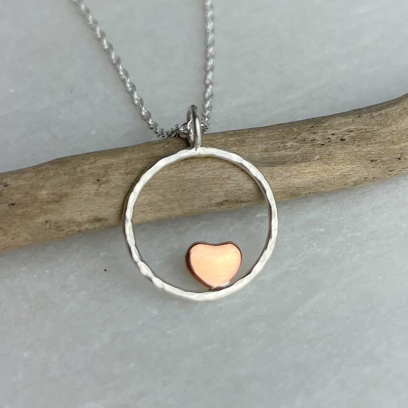 Silver hammered circle pendant with rose gold heart on chain