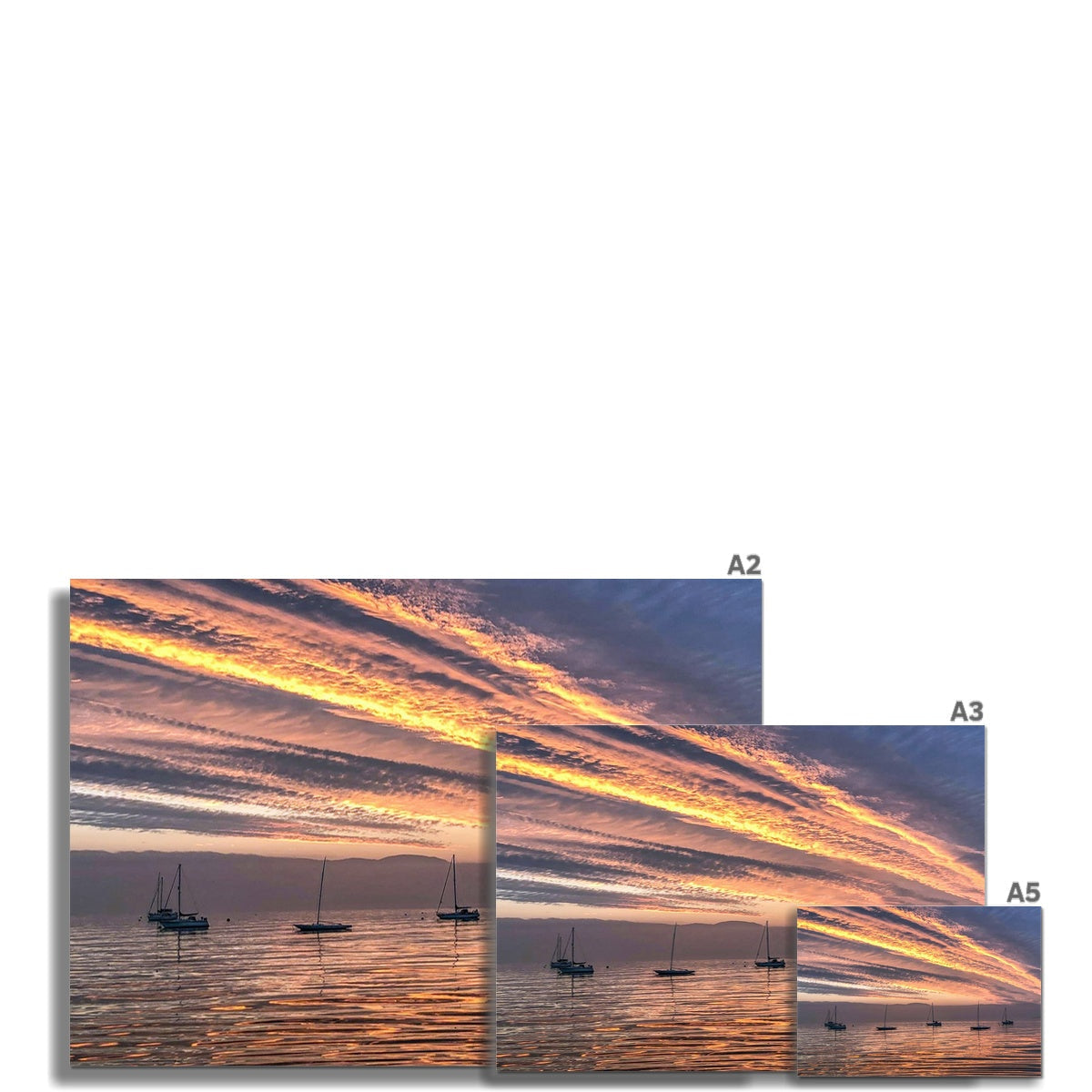 Vibrant fiery sunset with orange gold streaks over calm waters and silhouetted sailboats