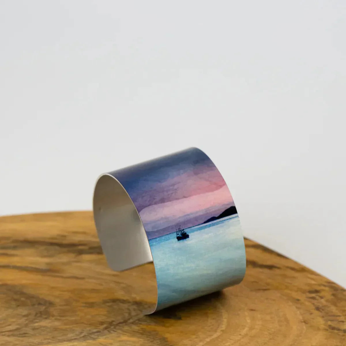 Fishing the Minch Bangle: sleek metallic cuff with serene sunset over water and boat