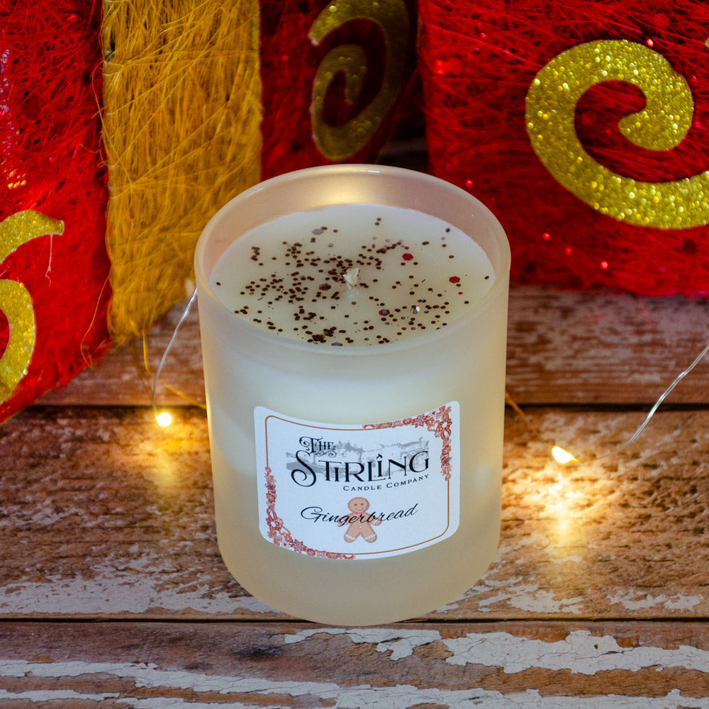 Gingerbread medium candle from The Stirring Candle Company with frosted glass jar, white wax, dark and red glitter