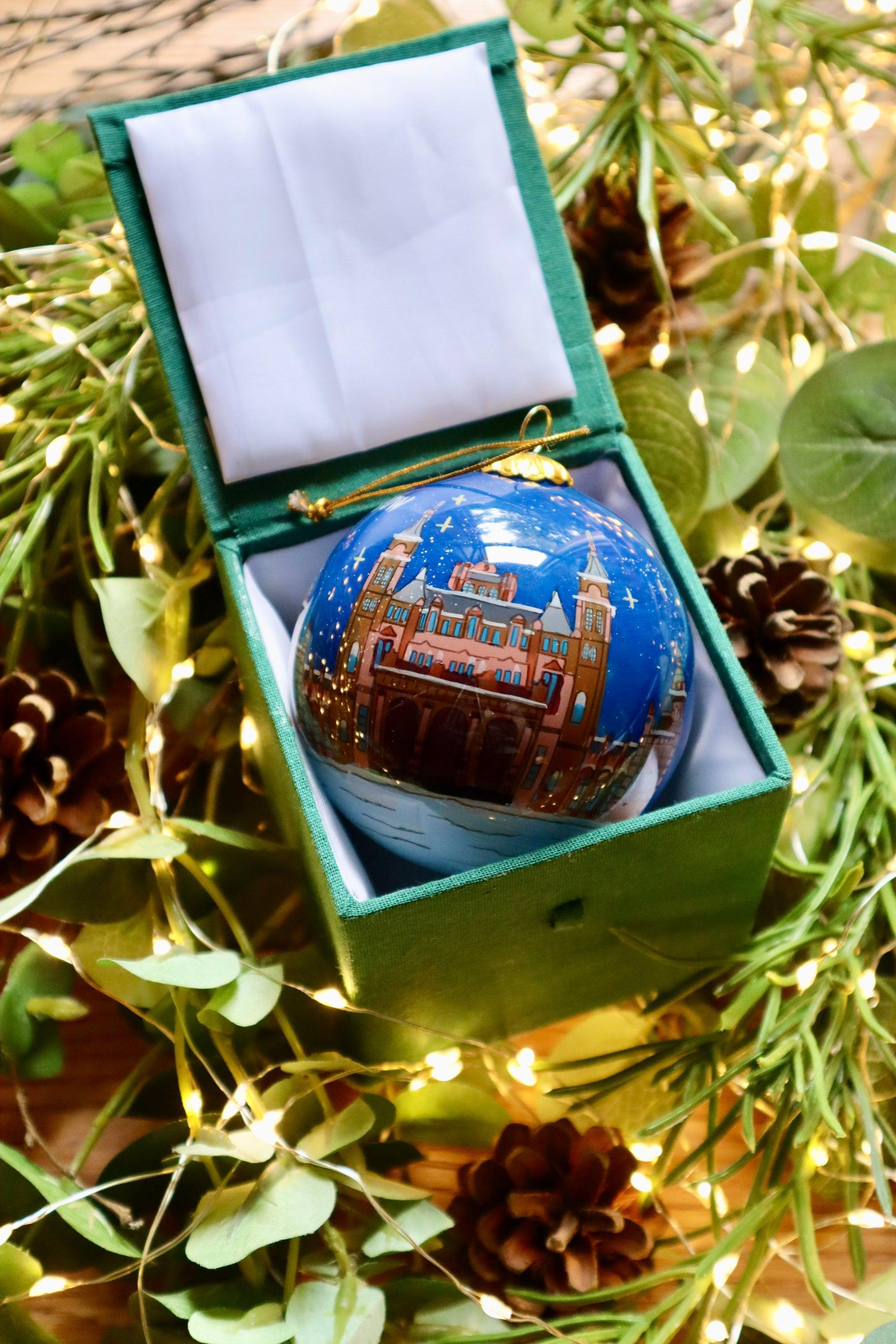 A glossy blue Glasgow City Christmas decoration bauble with a red-brick castle under a starry night in a velvet box