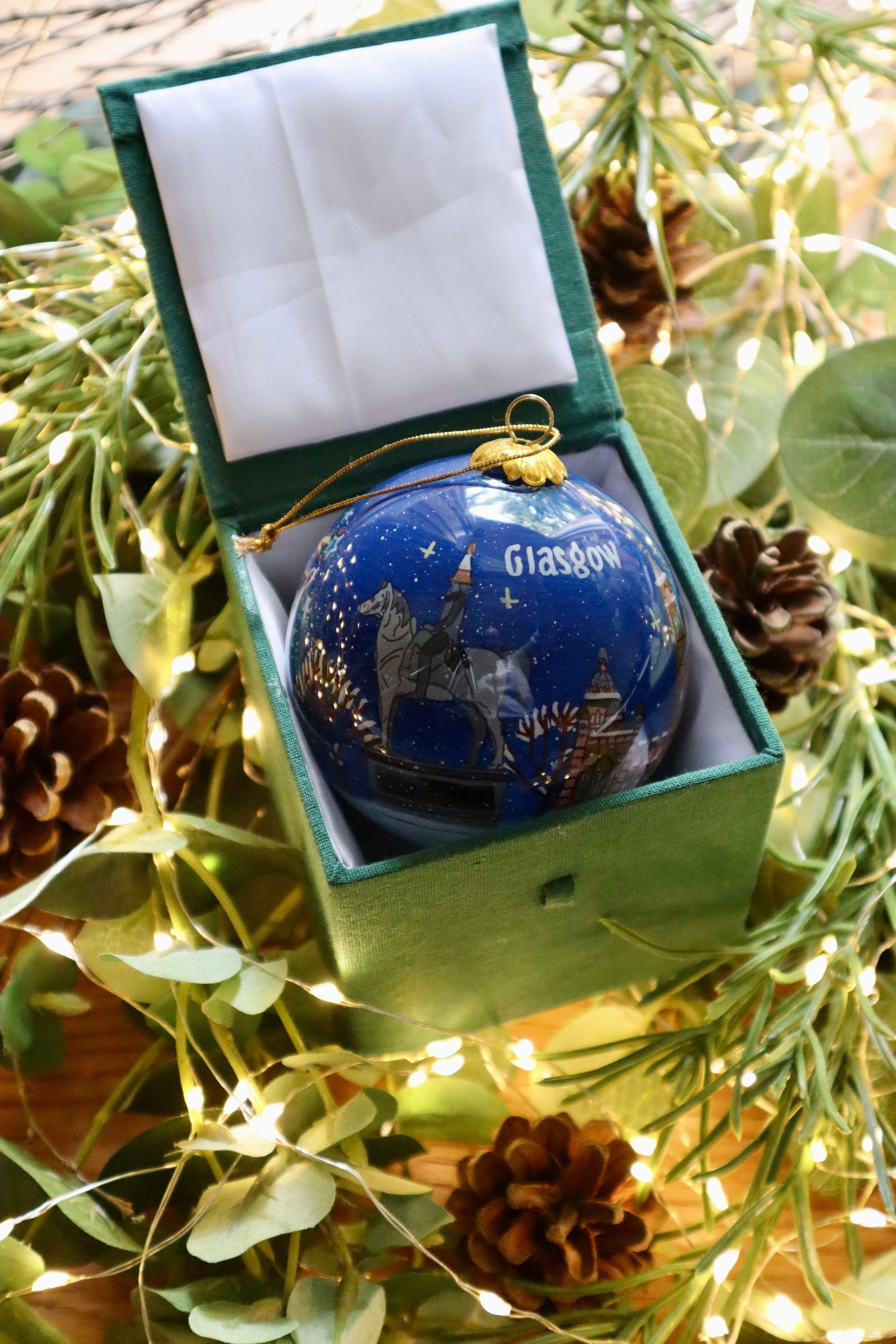 Deep blue glass christmas ornament with gold embossed glasgow city hall text in green velvet-lined box
