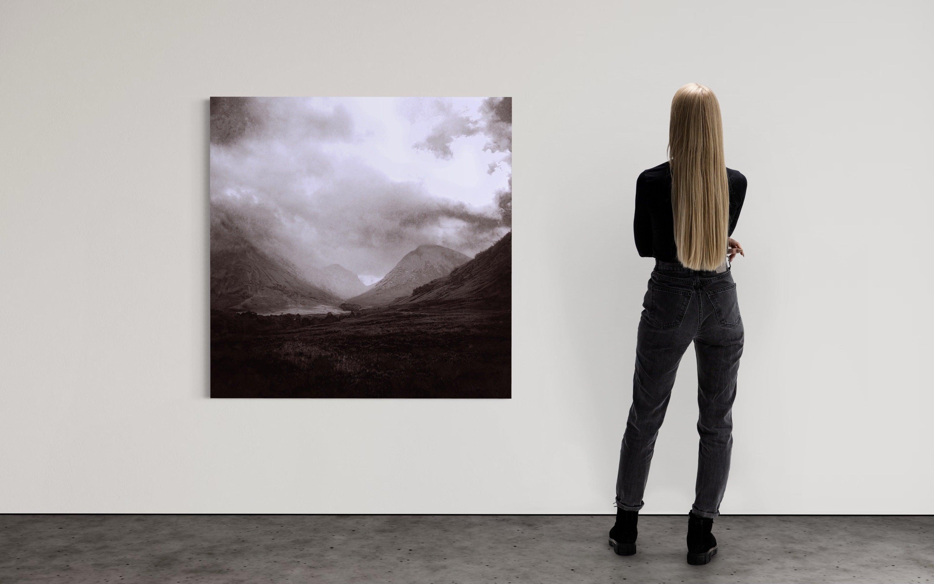 Woman with long blonde hair viewing Glencoe Mist abstract mountain landscape art in gallery