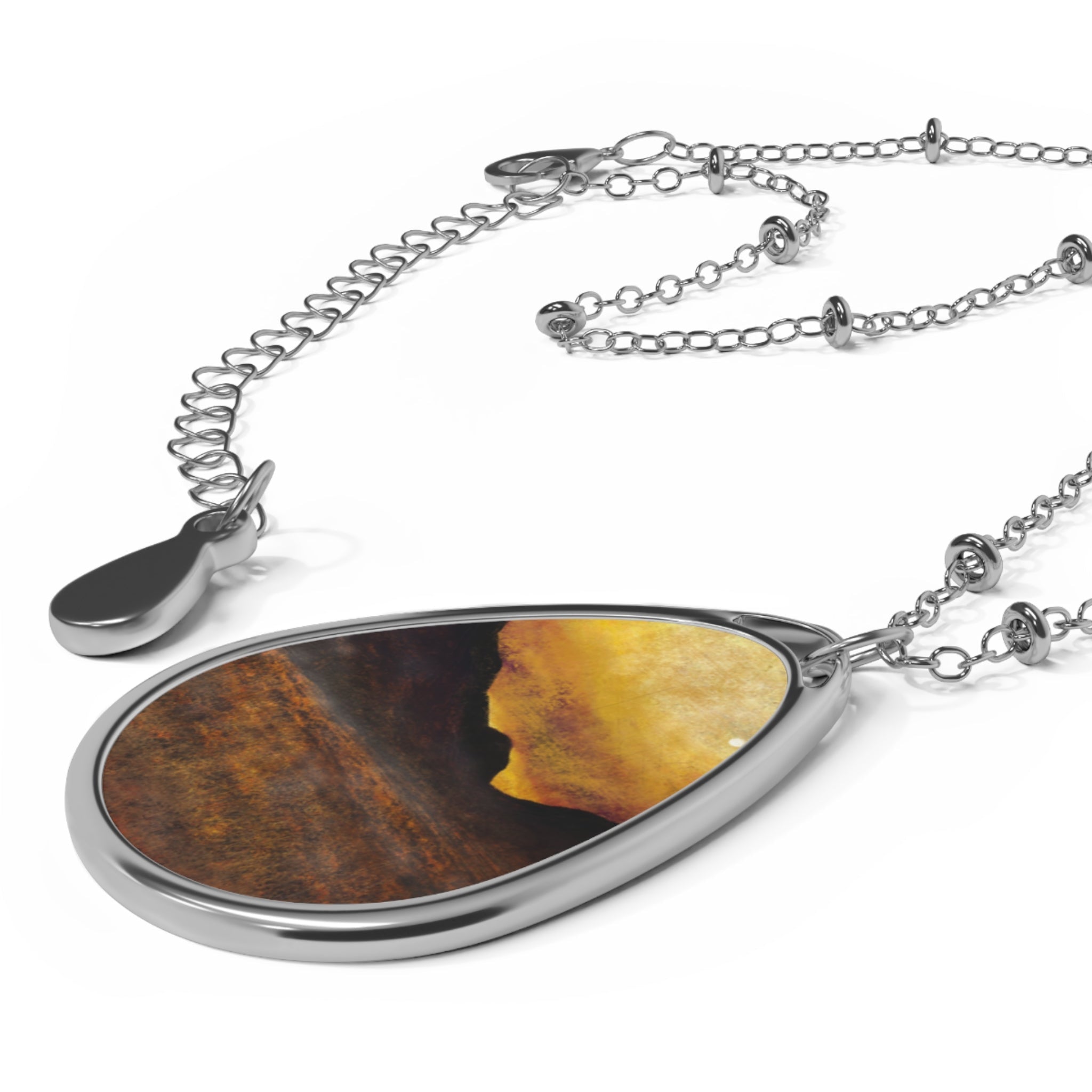 Silver teardrop pendant with dark and golden abstract design on a delicate silver chain