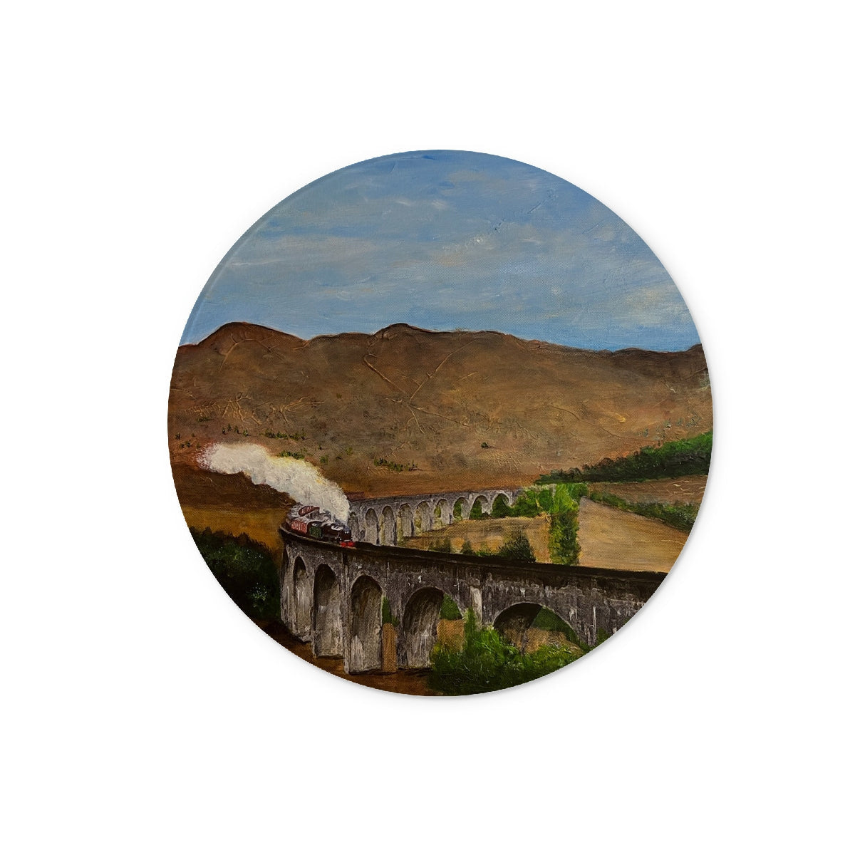 Round painting of a train crossing Glenfinnan Viaduct in a mountainous landscape on a glass chopping board
