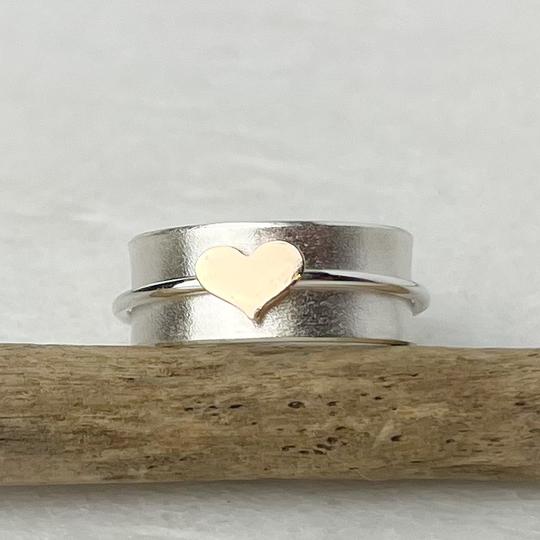 A gold heart spinning ring with a delicate silver band featuring a smooth metallic finish and minimalist design