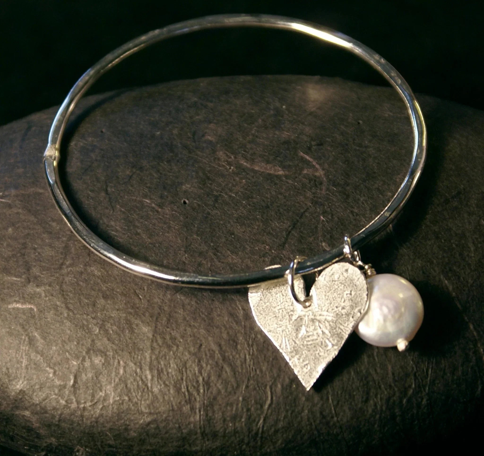 Silver-toned bangle bracelet with textured heart charm and single pearl in heart and pearl bangle design
