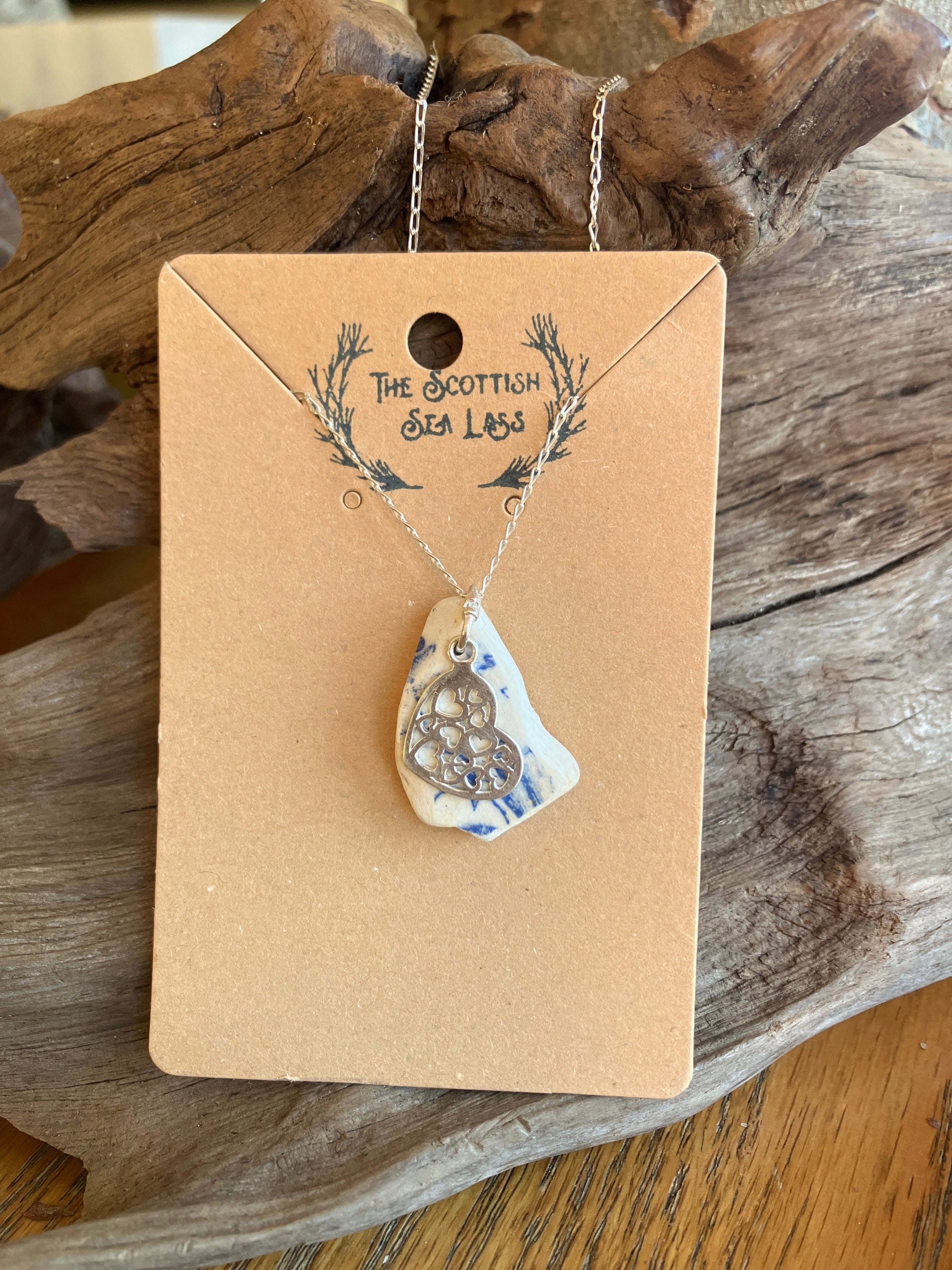 White and blue ceramic shard pendant with Celtic knot design on silver chain displayed on brown card