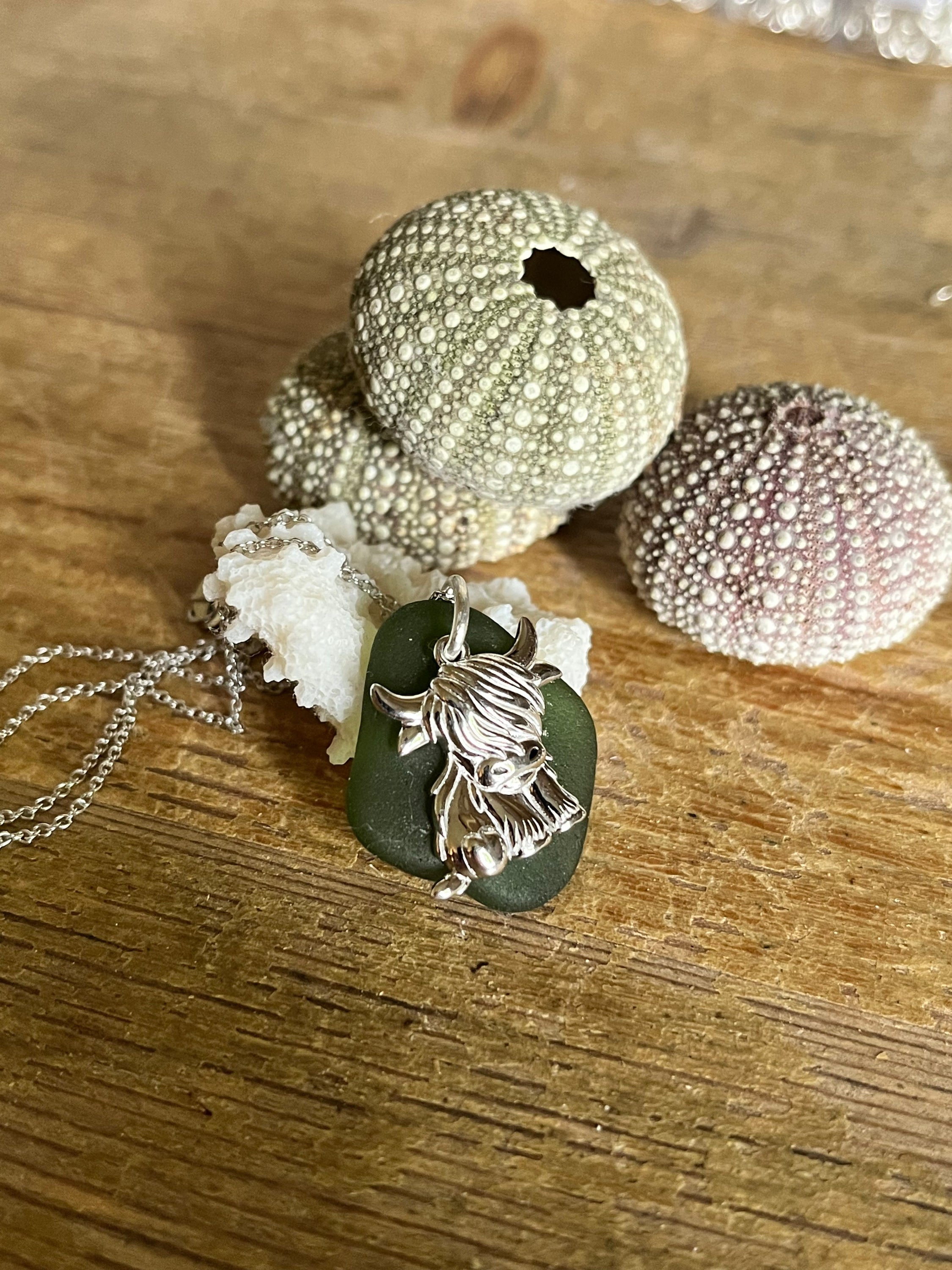 Silver 925 highland cow pendant on chain atop dark green sea glass