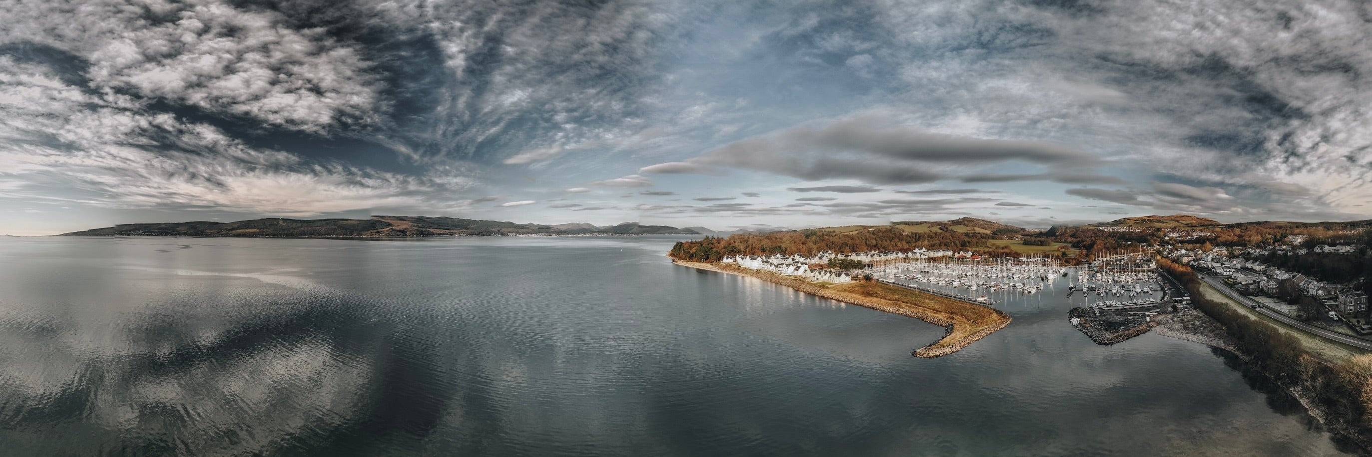 Panoramic view of Inverkip Marina with boats reflecting a cloudy sky in a calm bay
