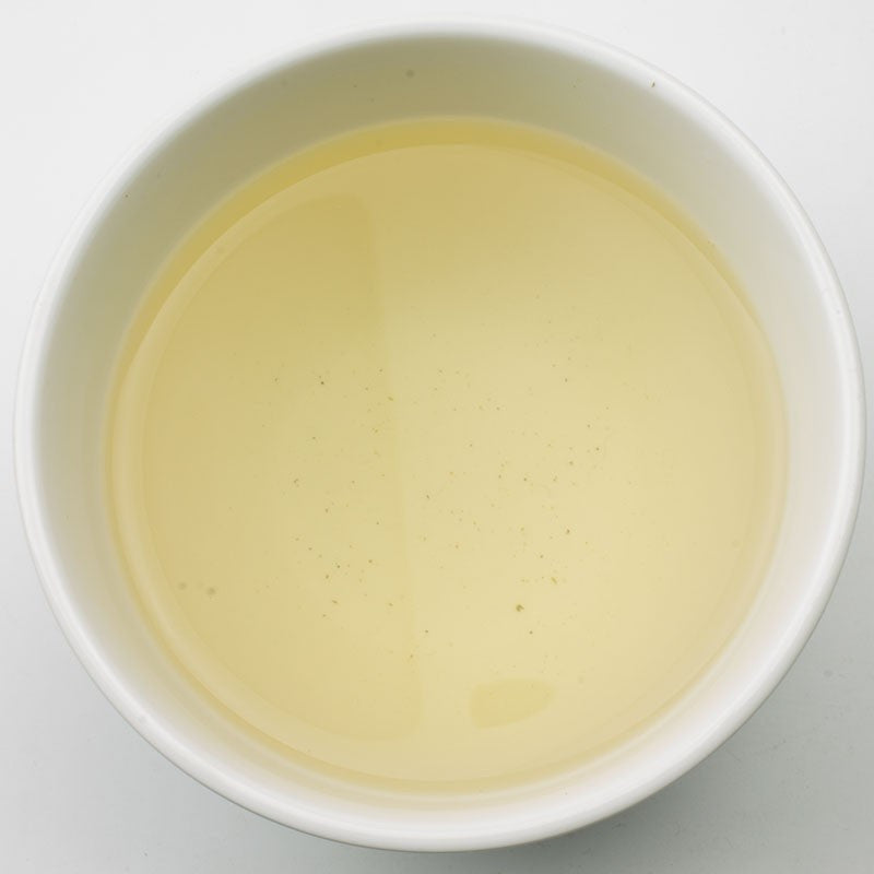 A white ceramic bowl filled with pale yellow jasmine dragon pearl green tea liquid