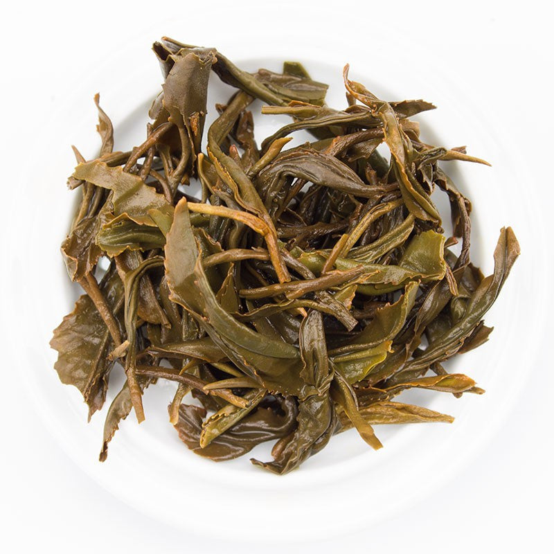 A pile of dark green slightly curled tea leaves with hints of brown and yellow from kinnettles gold scottish grown tea