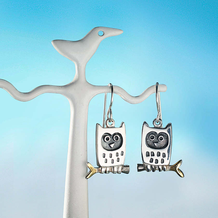 Silver little owl earrings with blackened facial features and gold-toned branch details in metal design