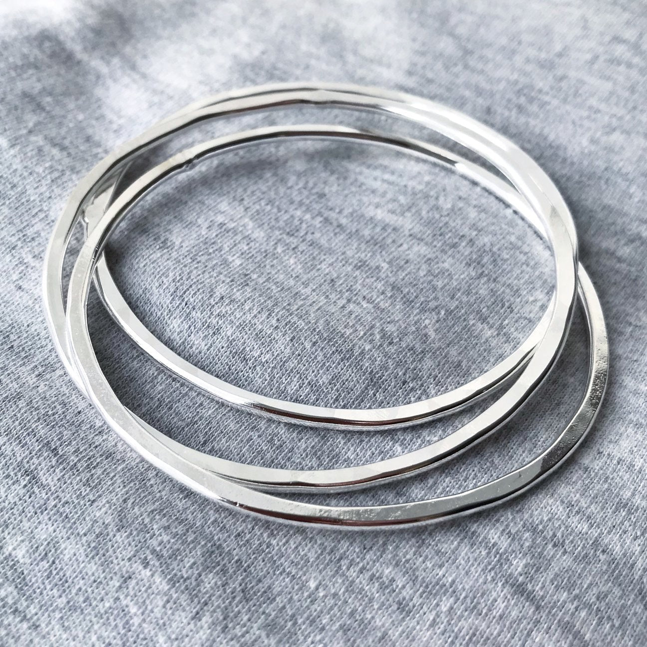 Three overlapping hammered silver bangles by Genna Miller Jewellery