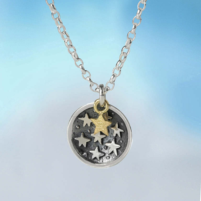 One in a zillion pendant silver-toned circular necklace with textured dark surface and silver and gold star-shaped charms