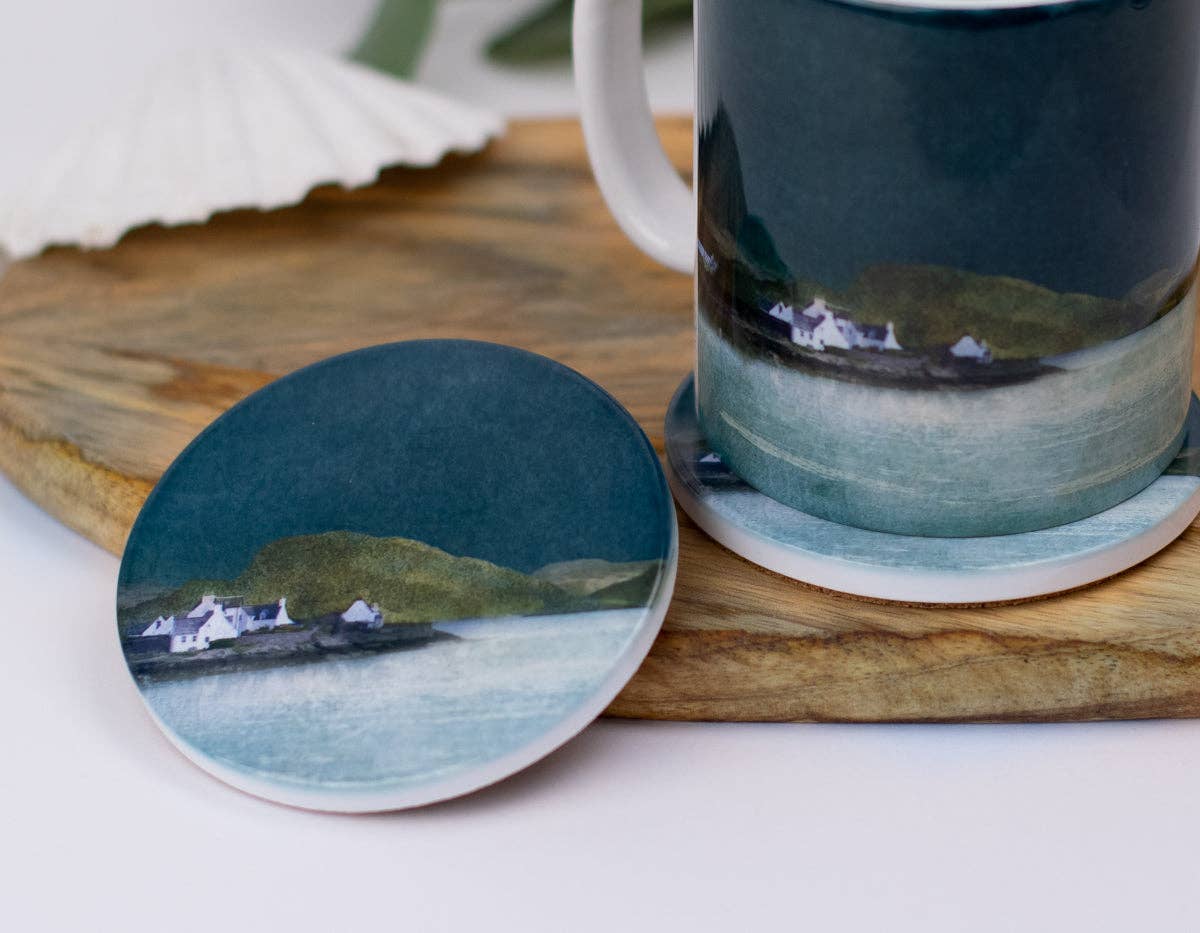 Plockton ceramic coaster featuring a painted coastal scene with white houses on green hills by blue water on dark teal background