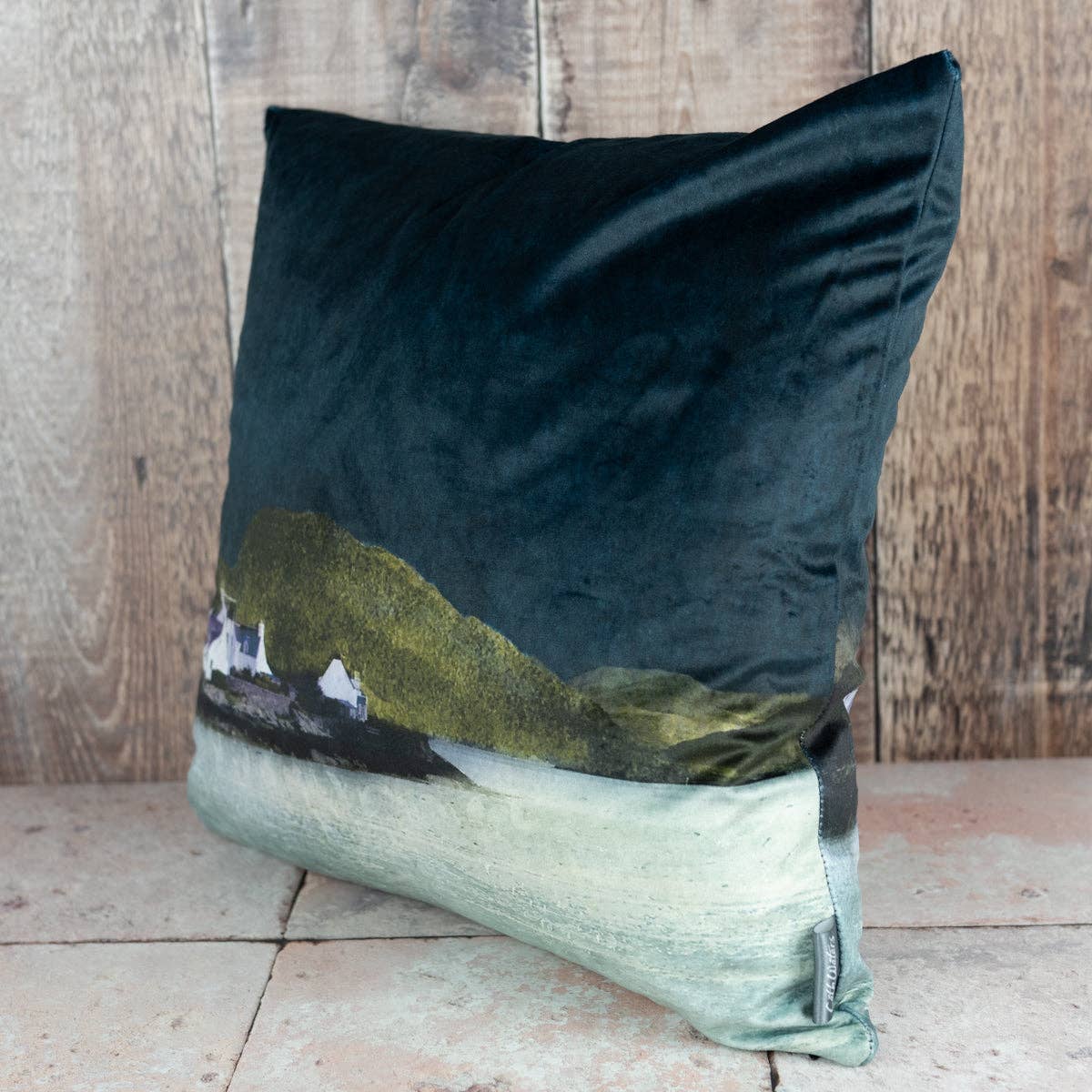 Plockton velvet cushion in dark teal with a printed coastal landscape of green hills and white buildings