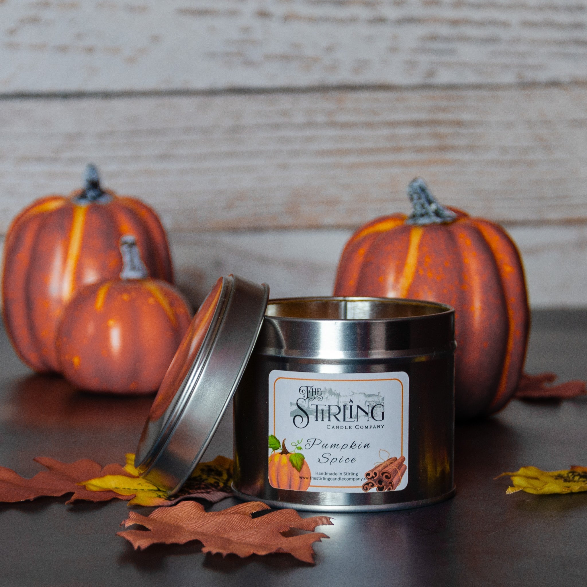 A metallic tin pumpkin spice travel candle by the string candle company with a silver lid and autumn-themed label