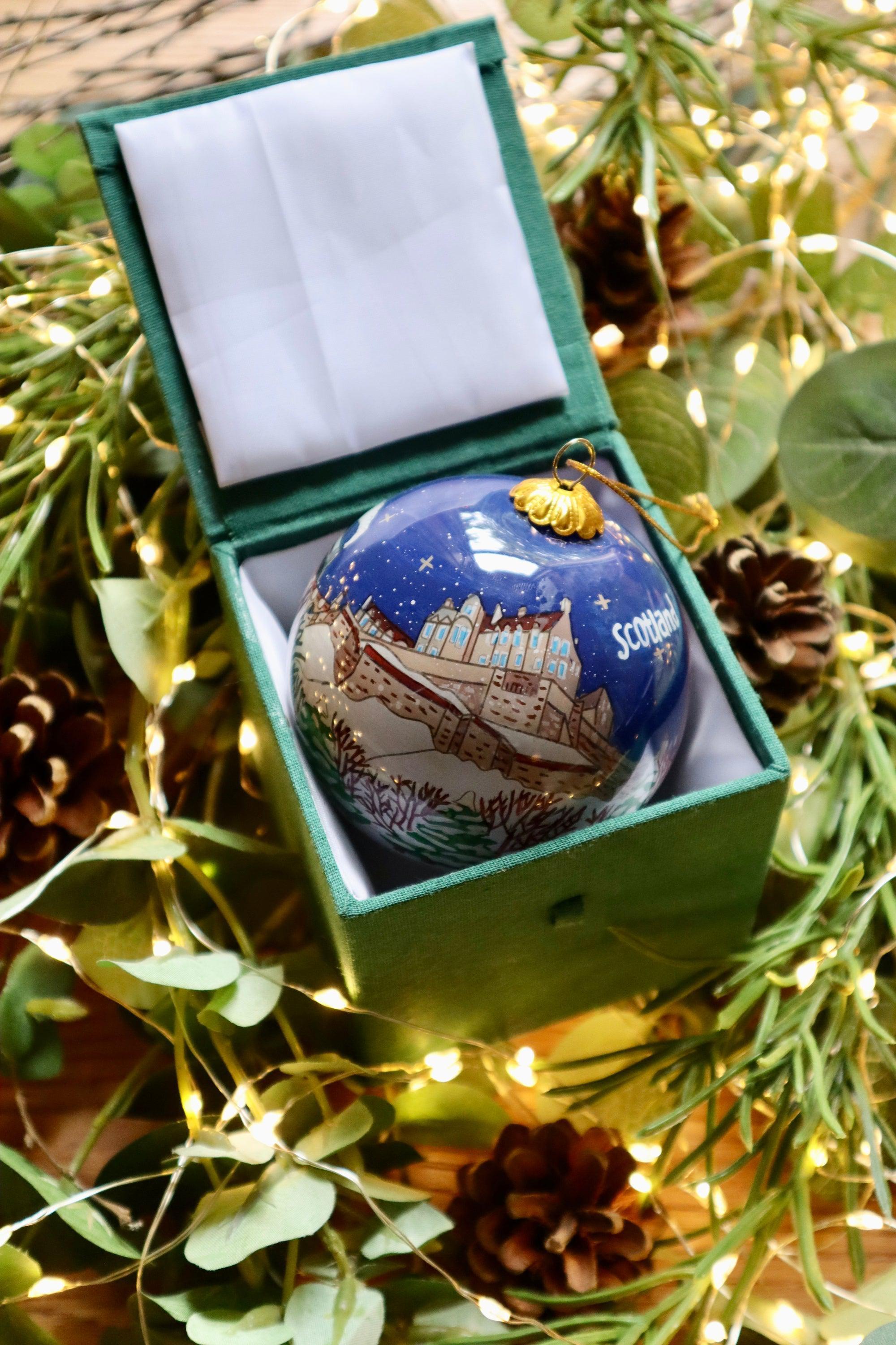 Blue glass christmas bauble with detailed edinburgh castle illustration snow design and scotland inscription golden cap