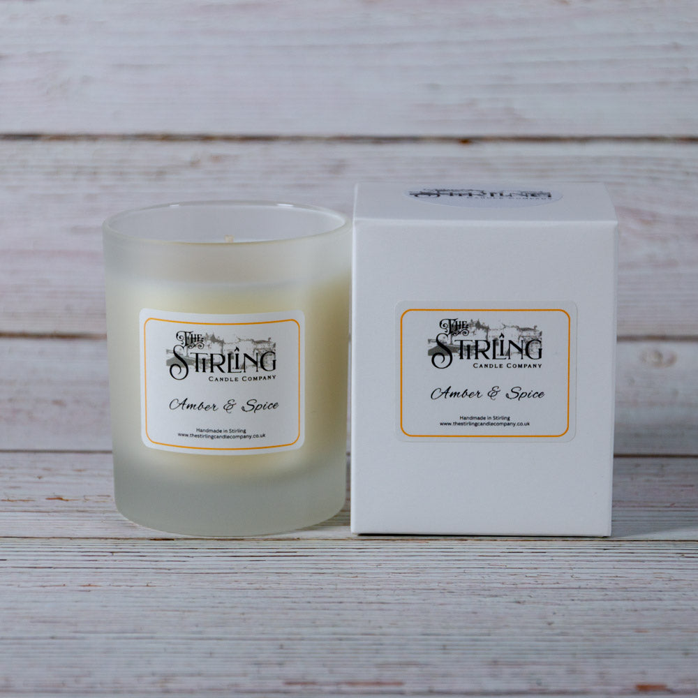 A frosted glass candle jar with creamy amber wax labeled amber and spice from the string candle company medium candle