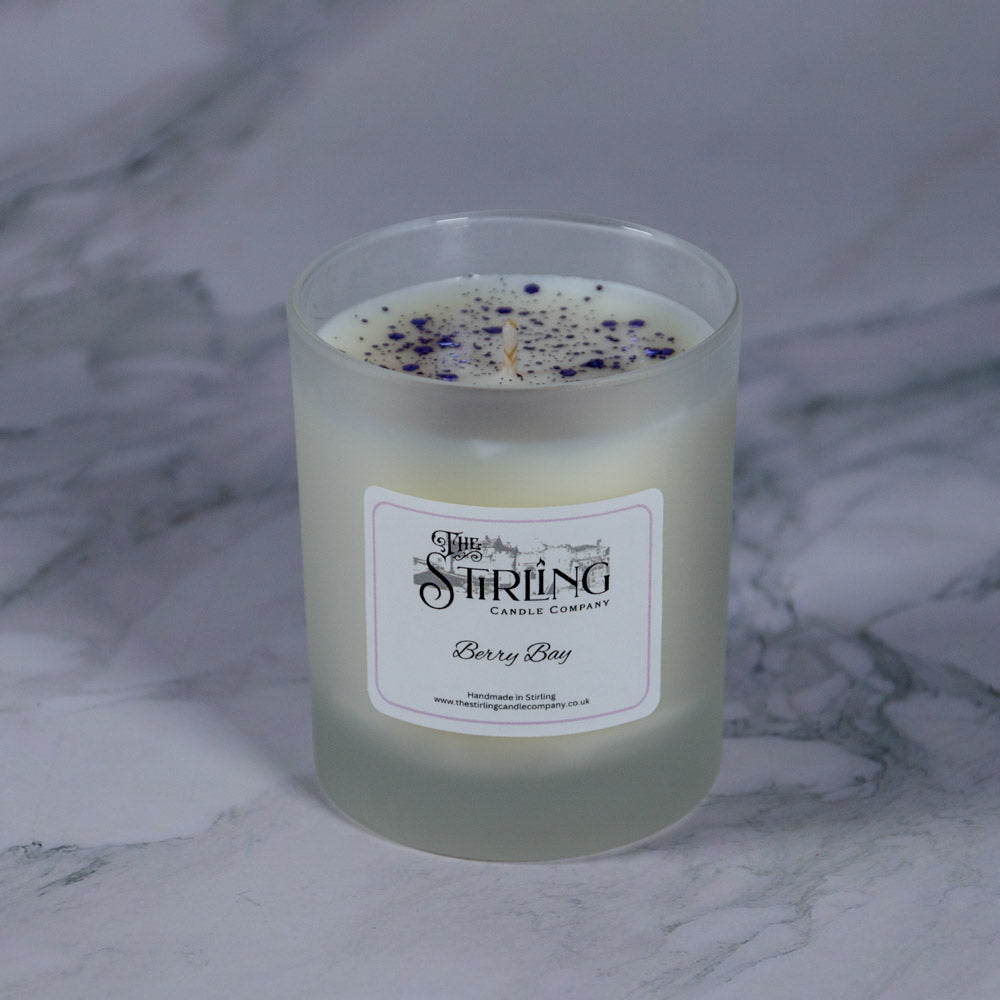 A frosted glass berry bay medium candle jar with white wax and purple speckles by stirling candle company