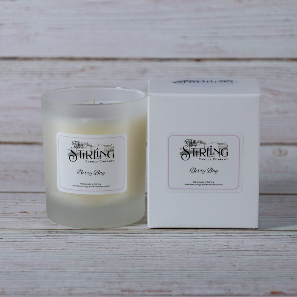 A frosted glass medium candle jar with white wax and a label reading berry bay from stirling candle company
